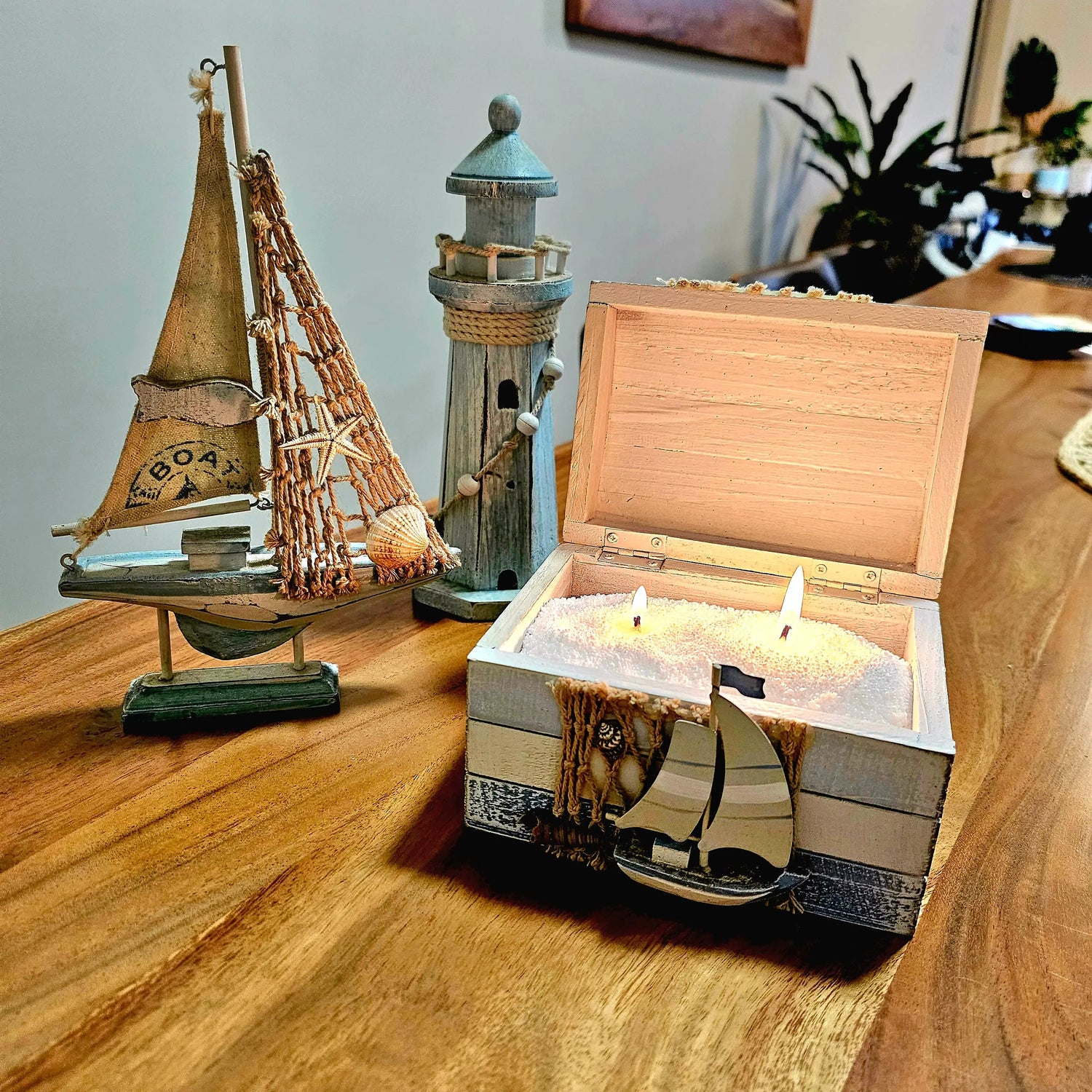 A treasure box filled with Solaire candle wax, with a model boat and lighthouse ornaments fitting into a beach theme. 